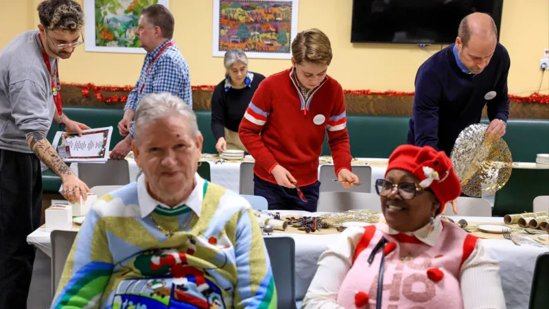 Trinta e dois anos depois, o Príncipe William e o Príncipe George ajudam a arrumar a mesa para o almoço de Natal da instituição